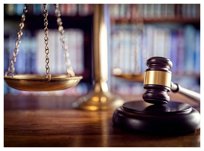 A judge 's gavel and scale in front of a law book.