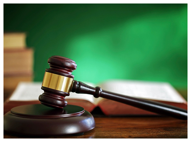 A judge 's gavel sitting on top of a wooden table.