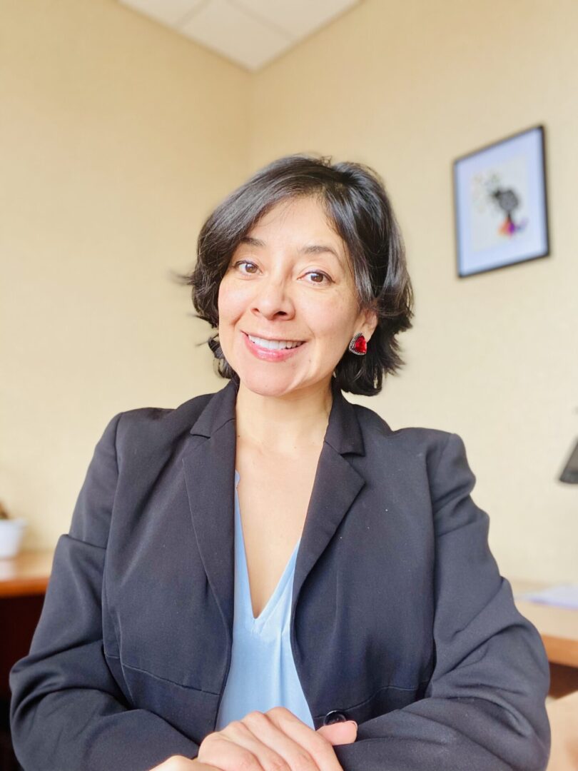 Woman in black blazer smiling at camera.