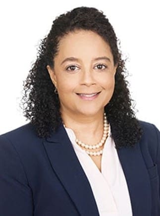 A woman in a blue blazer and pearl necklace.