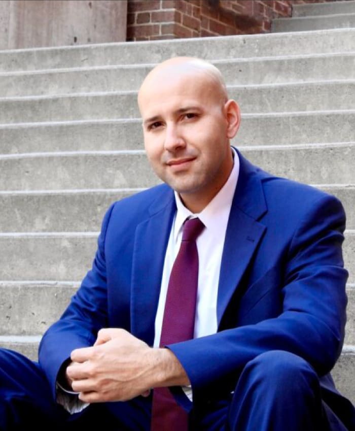 Man in a blue suit sitting on steps.